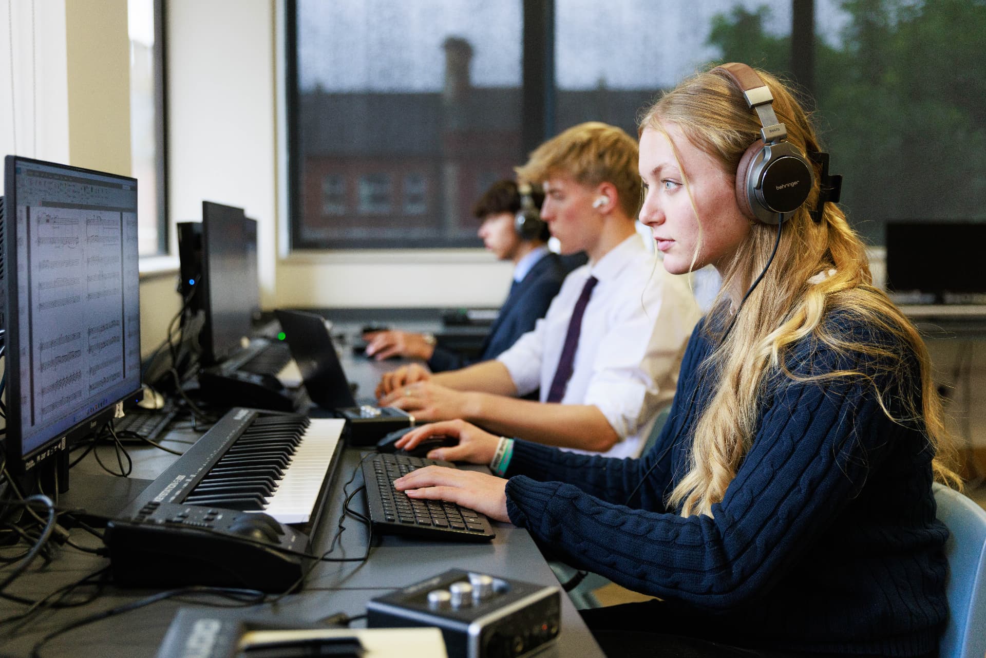 Students composing music using keyboards, headphones and specialist software