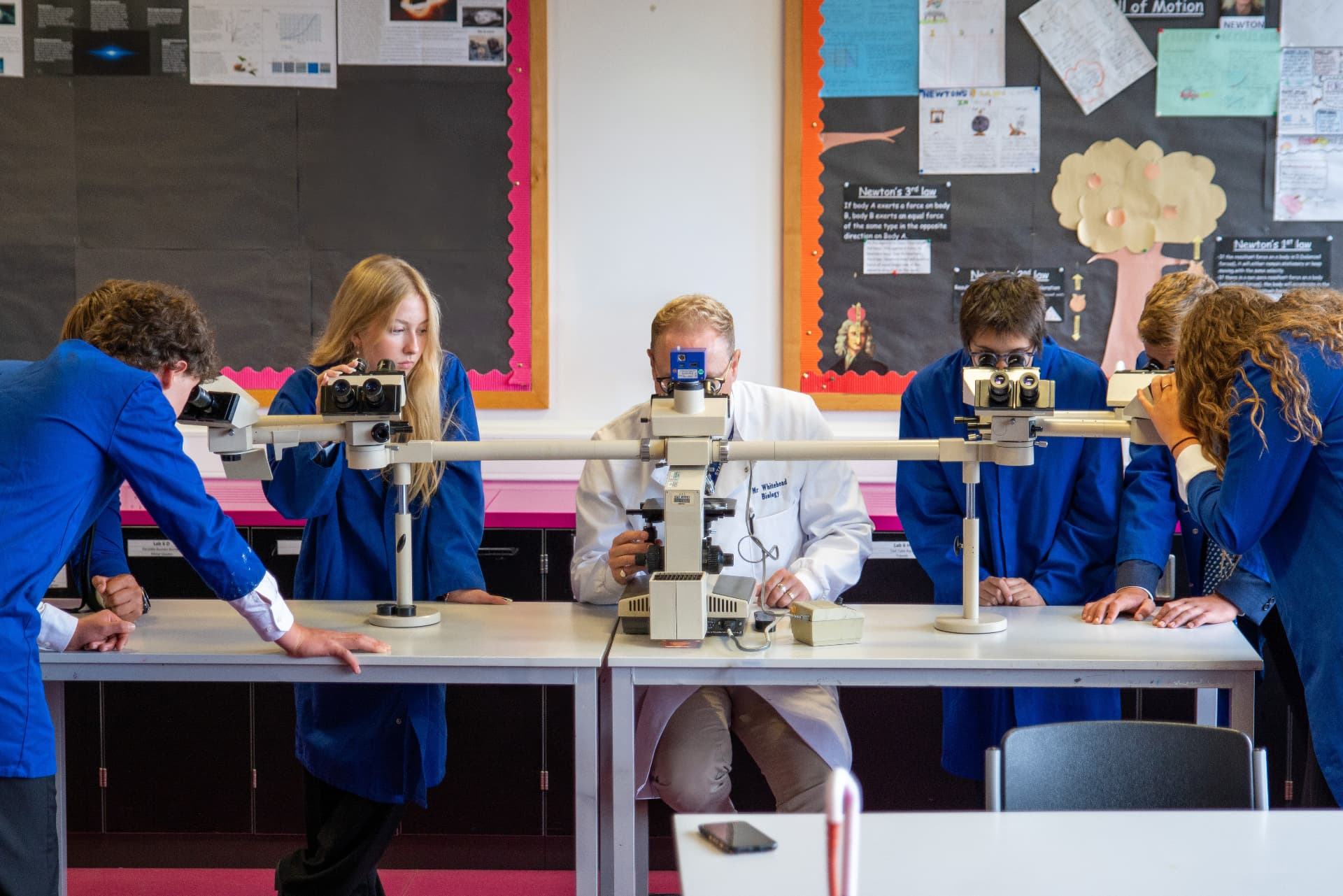 Sixth Form students using microscopes with their teacher in a science laboratory