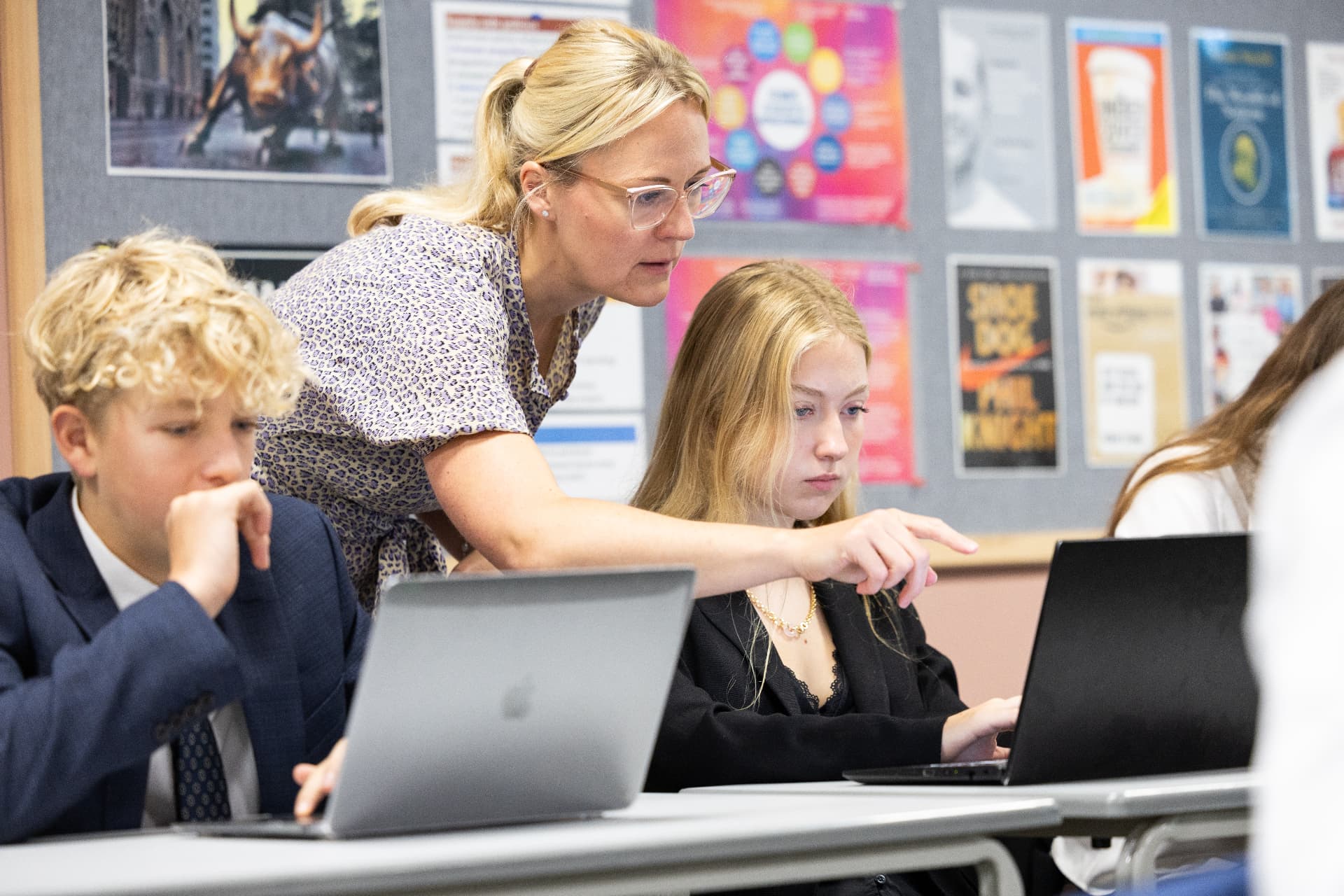 A teacher supporting Sixth Form students during a classroom lesson